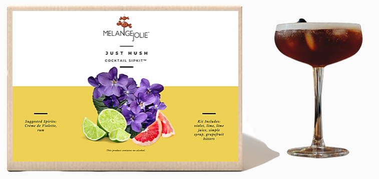 Mélange Jolie Just Hush Cocktail SipKit™ featuring a coupe glass, bar spoon, edible violets, and cocktail ingredients.